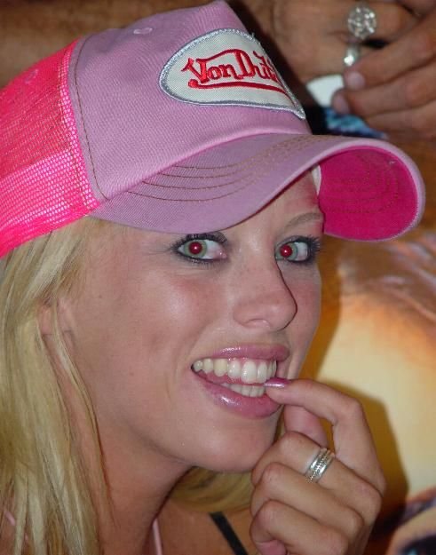 Close view of Brittney Skye in a pink trucker cap, one hand raised beside her face
